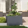 A modern outdoor patio with a large grey planter filled with plants, surrounded by outdoor furniture and decking. Produktbild-Vorschau