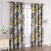 A pair of floral patterned curtains hanging in front of a window, with a bedside table and a lamp visible. Produktbild-Vorschau