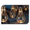 Close-up of several clear glass LED light bulbs hanging in a dark outdoor setting, with smaller lights in the background. Anteprima dell’immagine prodotto