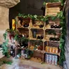 A display of wooden crates used as shelving for wine bottles and cans, decorated with artificial greenery. Produktbild-Vorschau