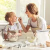 A mother and daughter are baking together in a kitchen, playfully smearing flour on each other's noses. Produktbild-Vorschau