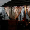 Icicle lights hanging from a thatched roof structure, with people sitting on a bench in the background. Anteprima dell’immagine prodotto