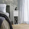 A bedside table next to a bed with a smartphone on it. Náhľad obrázku produktu