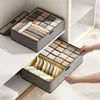 Two fabric storage organizers with multiple compartments for clothing are shown in a closet or shelving unit. One organizer is on a shelf, and the other is being pulled out by hands. Produktbild-Vorschau