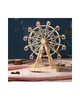 A wooden model of a Ferris wheel is displayed on a pink cloth with a dark blue background. Náhled obrázku produktu
