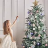A young girl decorating a Christmas tree with snowflake ornaments. Produktbild-Vorschau