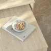 A close-up shot of a set of nesting tables with a book and a bowl of pistachios on the lower table. Produktbild-Vorschau