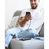 A man is sitting on a couch, holding a smartphone that is connected to a power bank. Anteprima dell’immagine prodotto