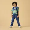 A young boy wearing a backpack stands against a plain background. Produktbild-Vorschau
