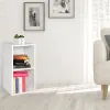 A white corner shelf unit with books and plants, placed in a room with a sofa and a window. Produktbild-Vorschau