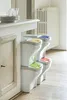 A set of four stacked trash cans with different colored lids, placed next to a kitchen counter. Náhľad obrázku produktu