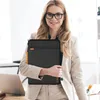 A woman in a business suit holds a laptop sleeve in an office setting. Anteprima dell’immagine prodotto