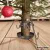 Close-up of a Christmas tree stand with a red ornament hanging nearby. Náhled obrázku produktu