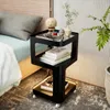 A black metal and glass bedside table with LED lighting, placed next to a bed. Produktbild-Vorschau