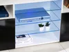 A media console with glass shelves and LED lighting, displaying a DVD player and decorative plants. Produktbild-Vorschau
