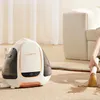 A person is using a portable carpet cleaner to remove a stain from a carpet next to a sofa. Podgląd zdjęcia produktu