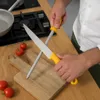 A person is sharpening a knife on a wooden cutting board in a kitchen. Produktbild-Vorschau