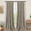 Two taupe-colored curtains hang from a black rod in front of a window. A small table with decorative items is visible to the right, and a potted plant is to the left. Produktbild-Vorschau
