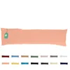 A long pillow with a peach-colored cover and a tag attached to the left end. Below the pillow are swatches of different colored pillow covers. Produktbild-Vorschau