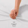 A hand is shown touching a white textured fabric, likely a bedsheet, with text indicating material composition. Produktbild-Vorschau