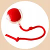 A red ball toy with a string, inside a white circle on a light beige background. Náhled obrázku produktu