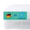 A close-up of a white mattress with a teal label showing certifications and origin information. Produktbild-Vorschau