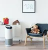 A white air purifier is placed on the floor next to a white cabinet in a room with a chair and stuffed animals. Anteprima dell’immagine prodotto