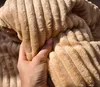A hand is holding a textured beige fabric. Produktbild-Vorschau