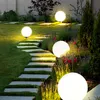 A garden path illuminated by spherical lights at dusk. Produktbild-Vorschau