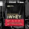 A large bag of protein powder is displayed in front of gym equipment. Produktbild-Vorschau