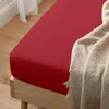 A close-up shot of a red fitted sheet on a wooden bed frame, with a beige blanket draped over the corner. Produktbild-Vorschau