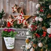 A Christmas-themed scene with a decorated tree and fireplace, featuring a potted plant with a decorative message. Produktbild-Vorschau