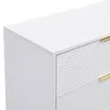 A close-up view of a white sideboard with gold handles and a ribbed texture on the drawers. Podgląd zdjęcia produktu