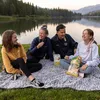 A family is having a picnic by a lake. Produktbild-Vorschau