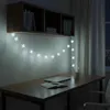 A desk with a laptop and notebook, illuminated by snowflake-shaped string lights. Náhled obrázku produktu