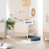 A nursery room with a crib, dresser, and plant. Produktbild-Vorschau