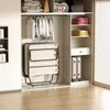 A foldable bed is stored in a closet next to folded clothes and luggage. Voir les images du produit