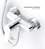 A close-up, angled view of a chrome shower faucet mounted on a white wall, with measurement lines and text indicating dimensions. Produktbild-Vorschau