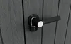 A close-up view of a black door handle with a padlock on a gray wooden door. Podgląd zdjęcia produktu