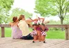 A woman and a child sitting on a wooden deck, looking at a tiered planter with flowers. Náhľad obrázku produktu