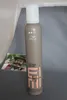A bottle of Wella EIMI Natural Volume Styling Mousse is shown in the foreground, with a blurred image of a person in the background. Produktbild-Vorschau