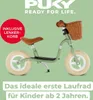 A green Puky balance bike with a brown basket and seat, set against a light green background with text overlays. Produktbild-Vorschau