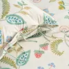 A close-up view of a bedding set with a floral and fruit pattern. Produktbild-Vorschau