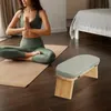 A woman meditating on a yoga mat next to a meditation bench in a room. Náhled obrázku produktu