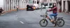 A woman is riding an electric bicycle on a city street. Produktbild-Vorschau
