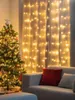 A decorated Christmas tree and a couch with pillows are in a room with string lights on the window. Voir les images du produit