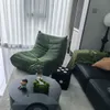 A modern living room with a green armchair, a black sectional sofa, and a coffee table. Produktbild-Vorschau