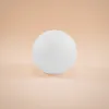 A white sphere is centered on a light peach background. Produktbild-Vorschau