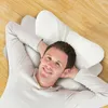 A man lying on his back on a wooden floor, resting his head on a butterfly-shaped pillow. Produktbild-Vorschau