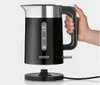 A hand is holding a black electric kettle over its base. Produktbild-Vorschau